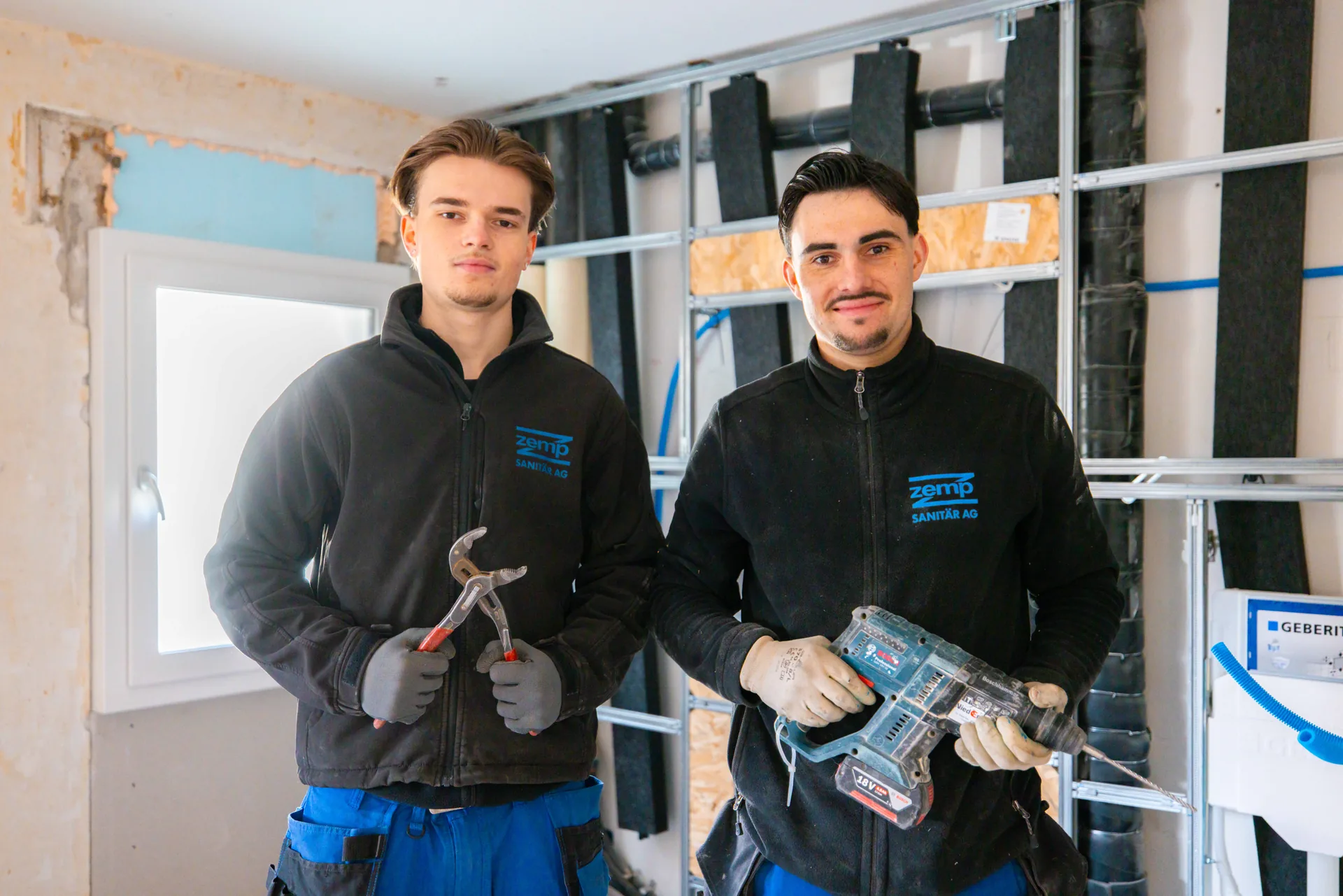 Zwei Zemp-Sanitärmonteure in der Werkstatt vor einer Geberit-Vorwand